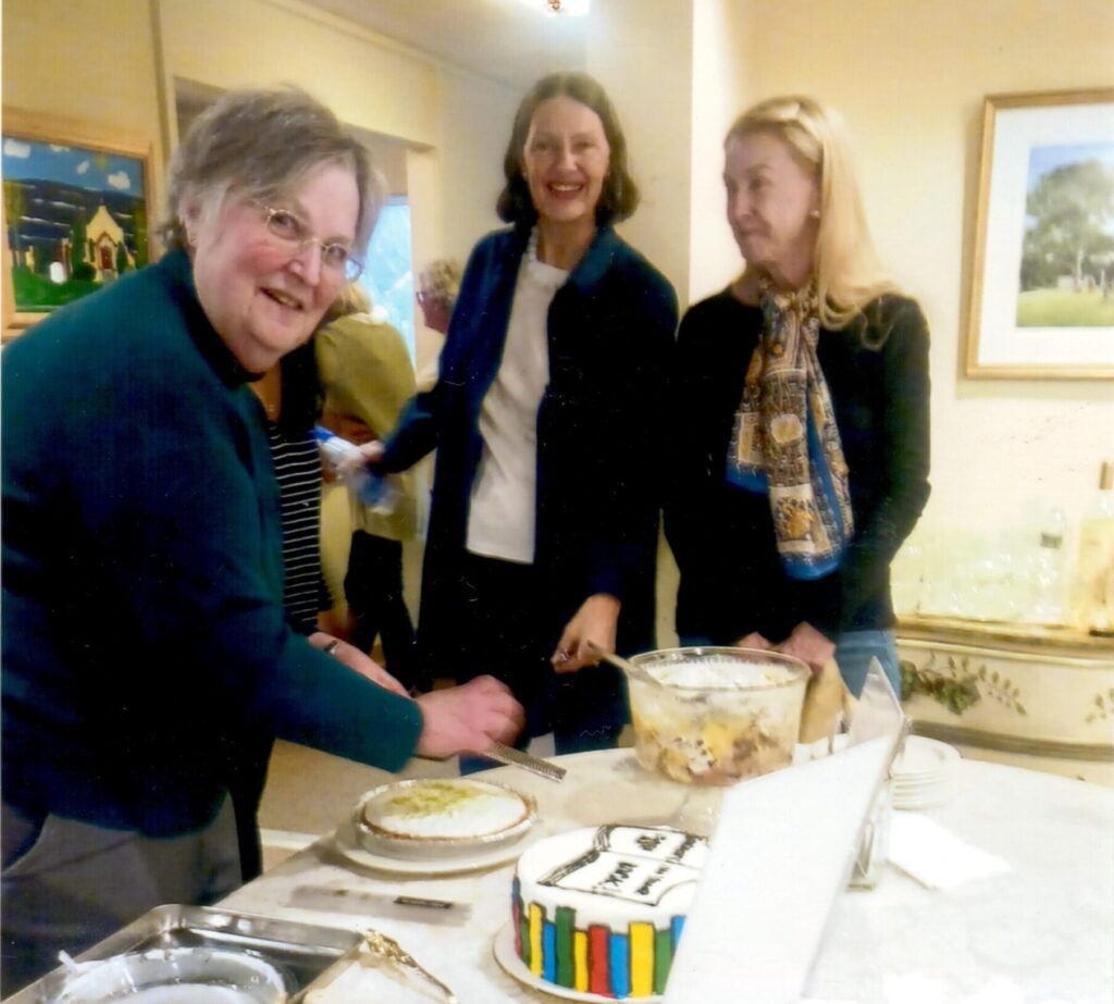 three women standing at a table filled with food for a milestone celebration marking the fiftieth saint johns book club meeting